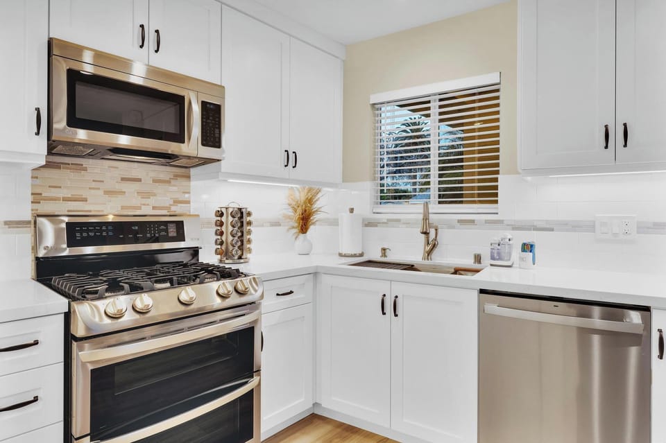 The ideal kitchen sink view. Large farmhouse stainless sink with beautiful views of tropical palms and lovely neighborhood.