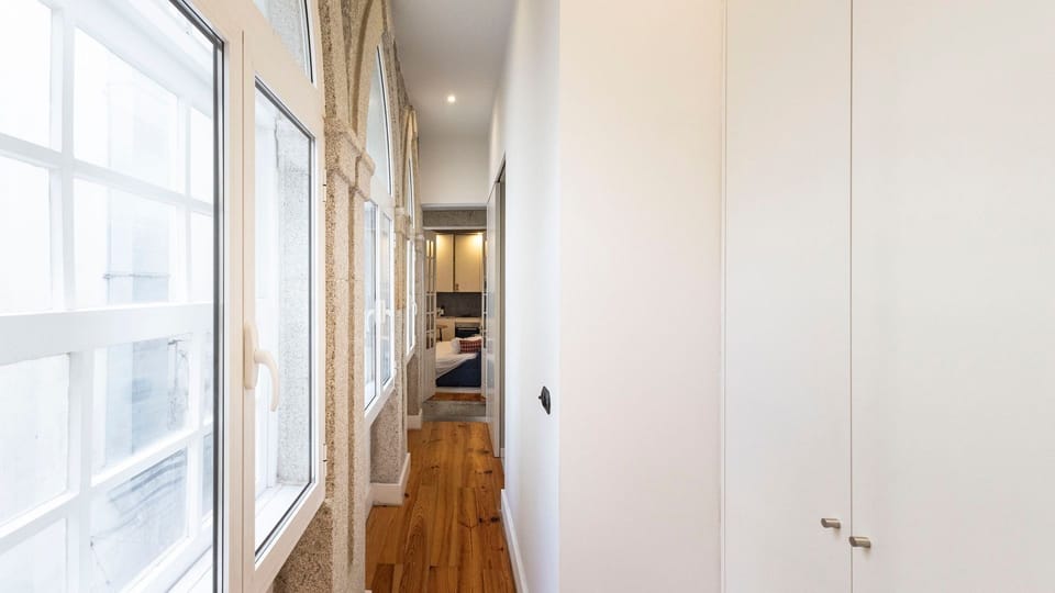 Stroll down this inviting hallway, bathed in natural light from charming arched windows, leading you to your private and comfortable spaces. The warm wooden floors guide your way through the apartment.