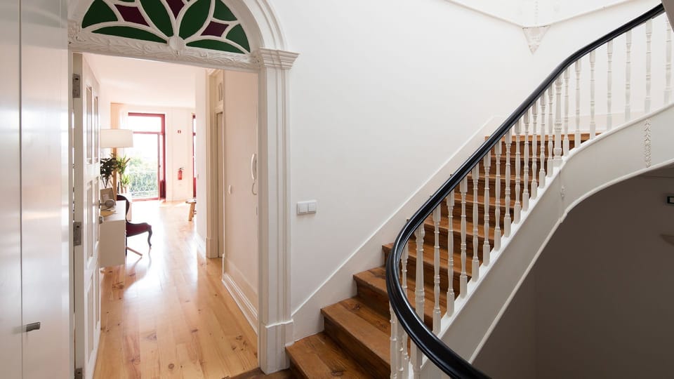 Step into a grand entrance featuring a beautiful curved wooden staircase, hinting at the charming spaces within and setting a tone of classic elegance from the moment you arrive. The arched doorway with stained glass adds historic character.
