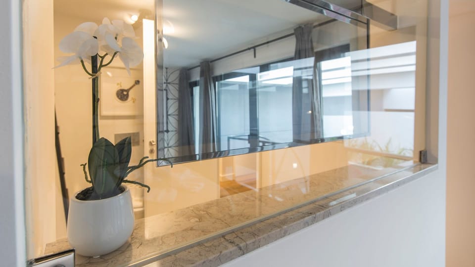 Enjoy a seamless flow between spaces, with natural light and views reflected from the living area, creating an open and inviting atmosphere. The thoughtful decor, including a delicate orchid, hints at a relaxing and stylish stay. #OpenConcept #ModernInter