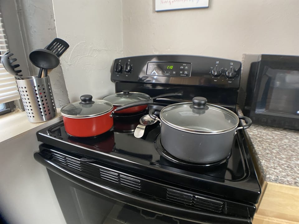 Furnished kitchen with pots & pans, bakeware, microwave, and dinnerware