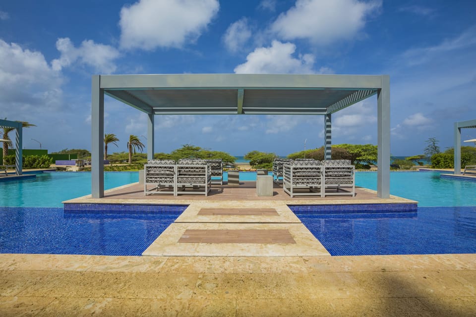 Modern poolside cabana featuring ocean views, shaded seating, and pristine turquoise waters—an ideal retreat for sun-soaked relaxation and tropical serenity.