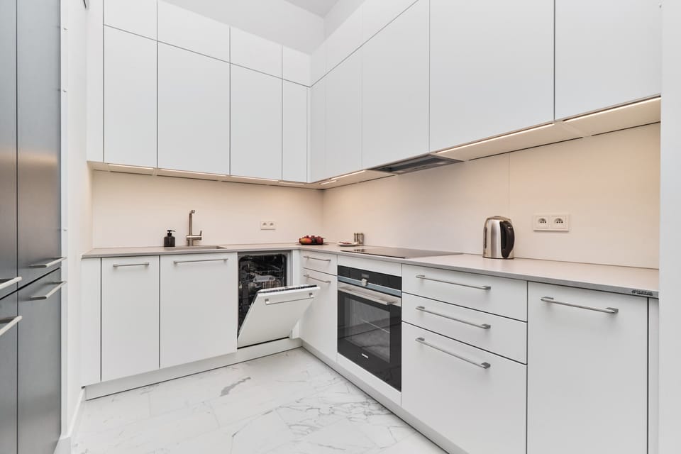 A compact kitchen with white cabinets, modern appliances, and a clean layout.
