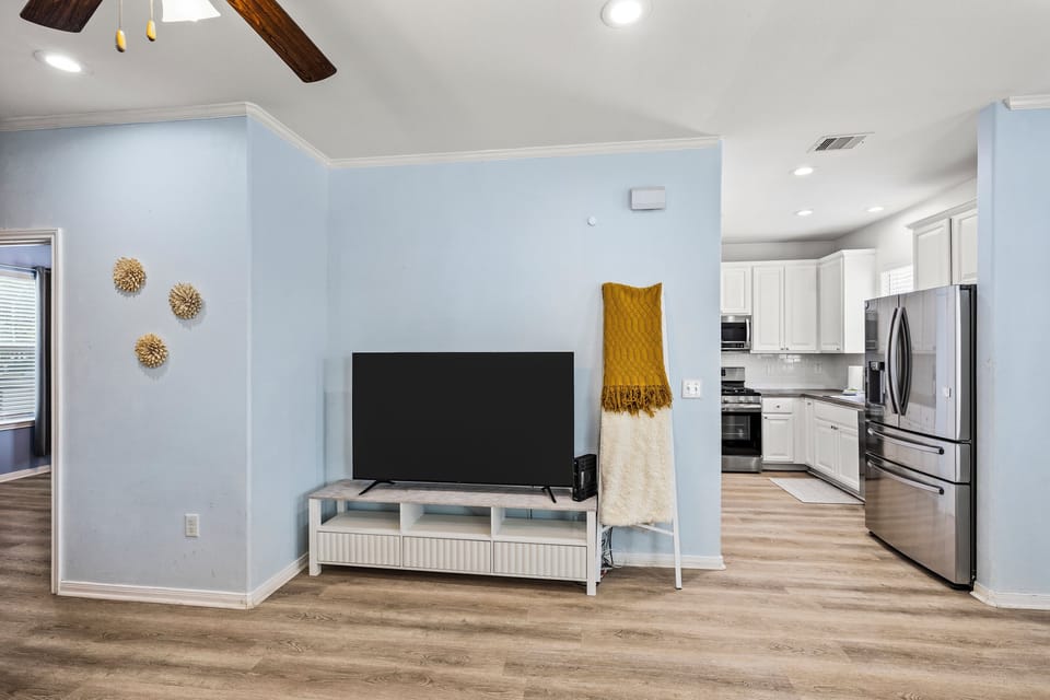 The open living area at Summer Bliss flows directly into the kitchen — smart TV, hardwood floors, and an easy layout for families and groups of up to 9.