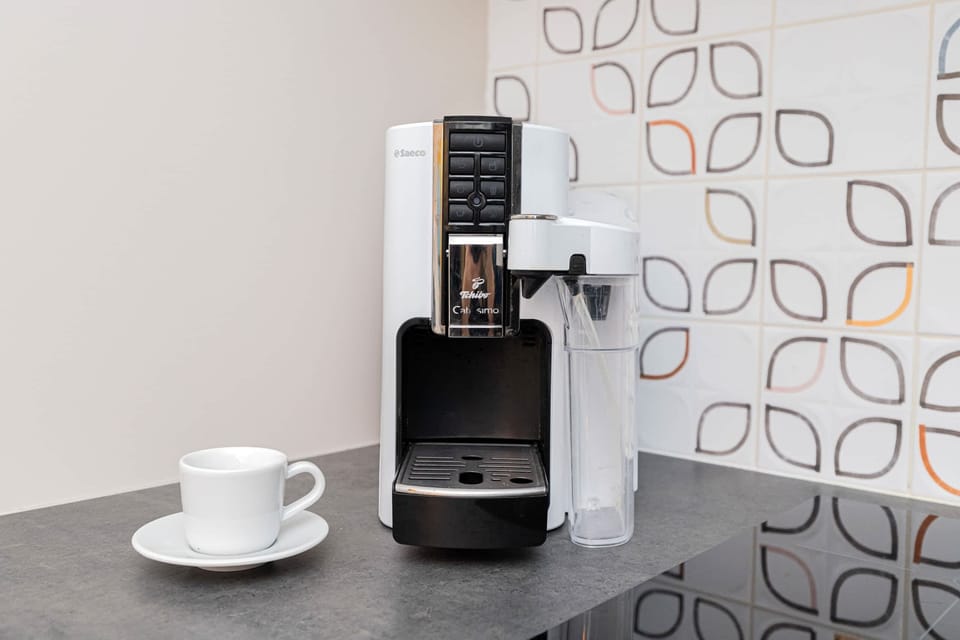 A dedicated coffee nook featuring a capsule coffee machine and a stylish backsplash. A functional and appealing space for coffee enthusiasts.