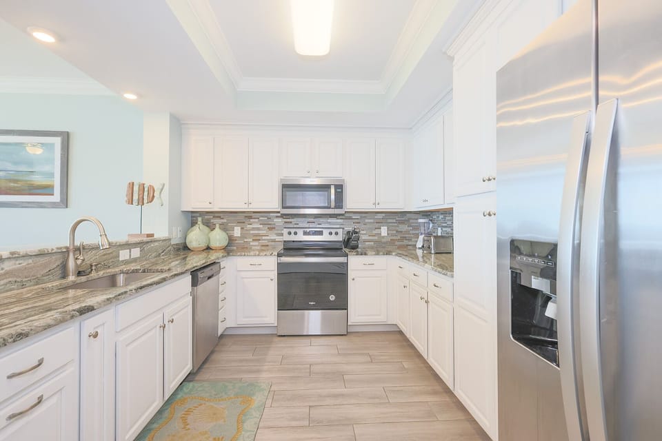 Prepare meals in this kitchen with elegant cabinetry, stainless appliances, and stylish backsplash