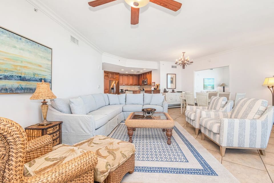 Sink into plush coastal sofas and let the soft breeze from your ceiling fan wrap around you in this sun-drenched, open-concept retreat designed for your ultimate comfort.
