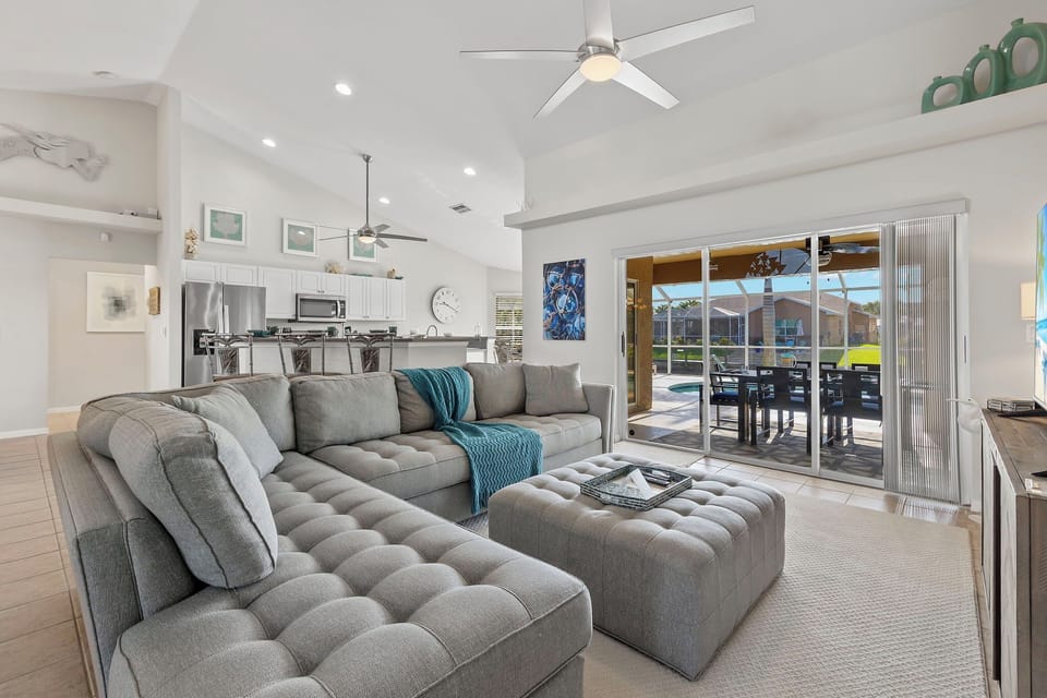 The spacious living room has plenty of seating & a view of the pool/water & a flat-screen TV (not pictured)