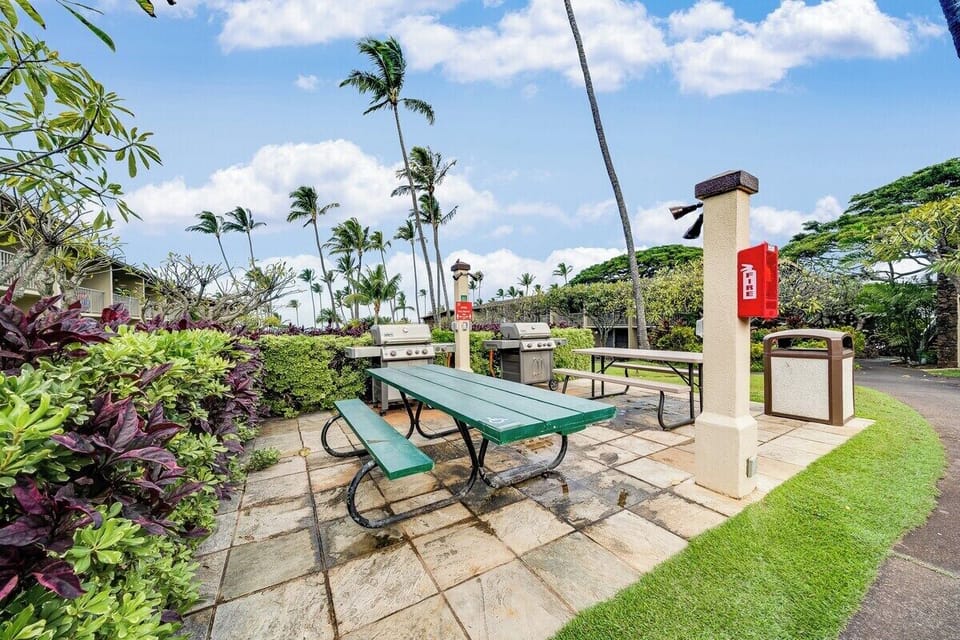 Fire up the grill at the community BBQ station, featuring clean stainless steel grills and picnic table seating.