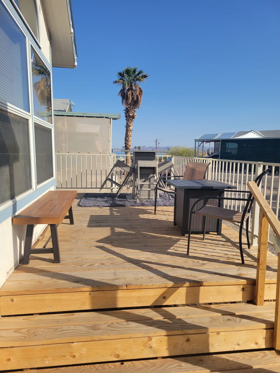 Front deck during day with bench, bistro table, firepit & chairs.