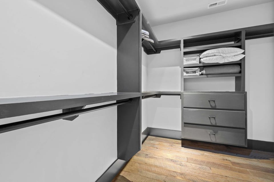 Spacious primary bedroom featuring a comfortable king-size bed, cozy seating area, Smart TV, large walk-in closet, and direct access to a private balcony.

