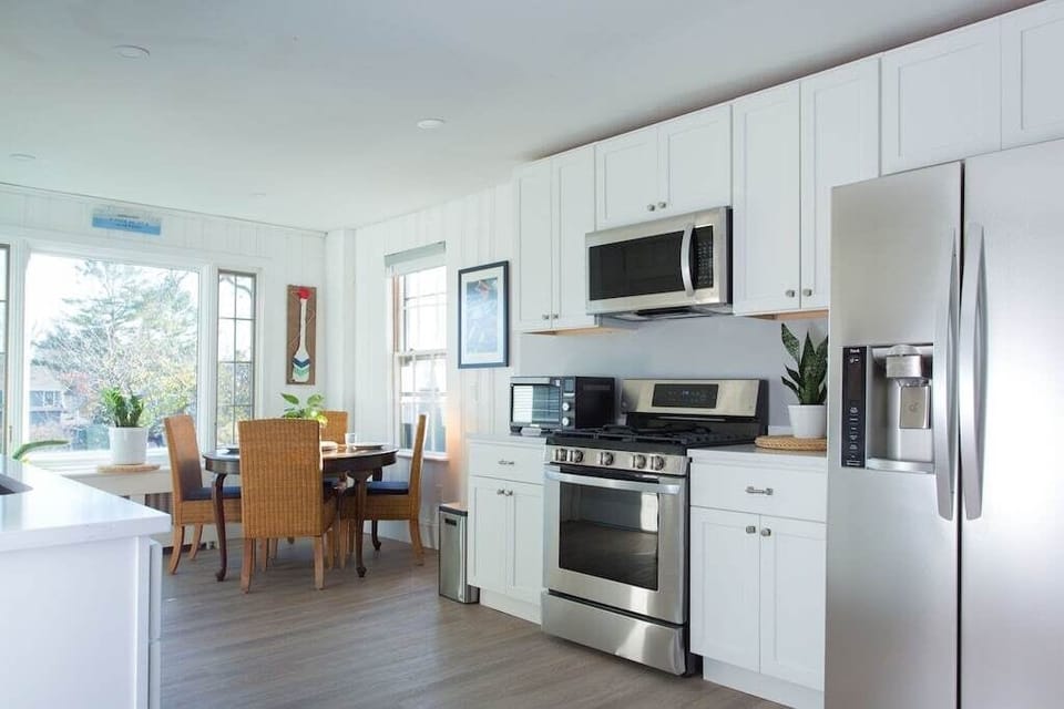 Kitchen: Bright and modern space with stainless steel appliances and sunlit dining area.