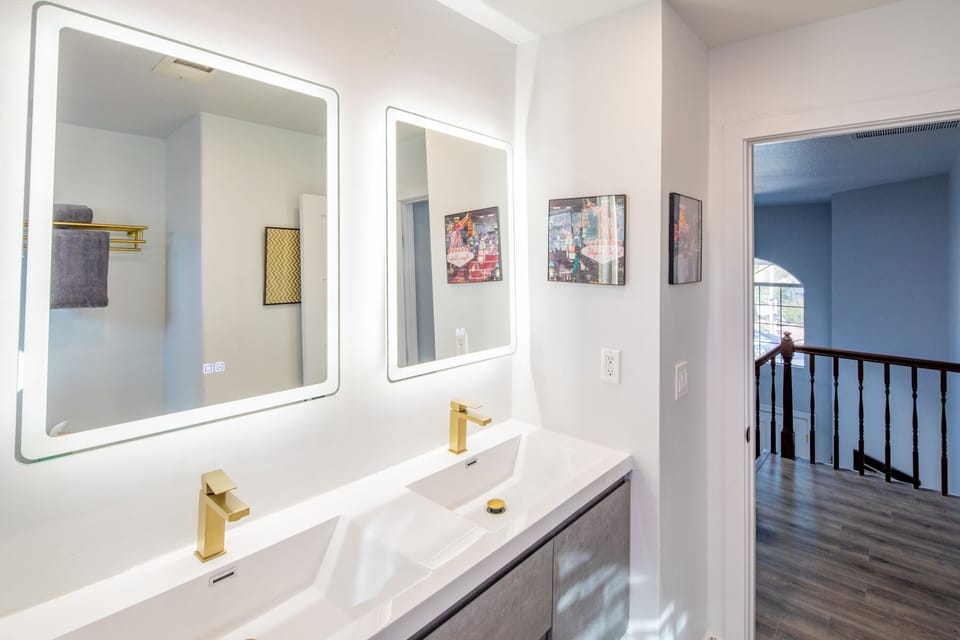 Classy double sinks w/ lighted mirrors that are also fog-less at the touch.