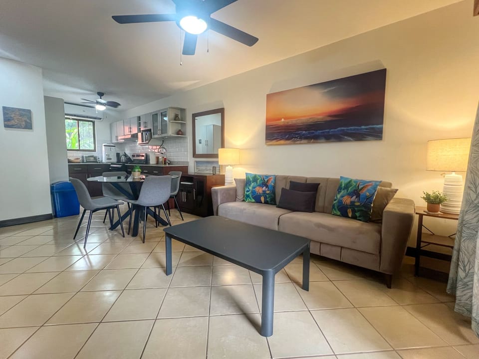 The condo has an open concept living space with the kitchen, dining and living room flowing out to the shaded patio.