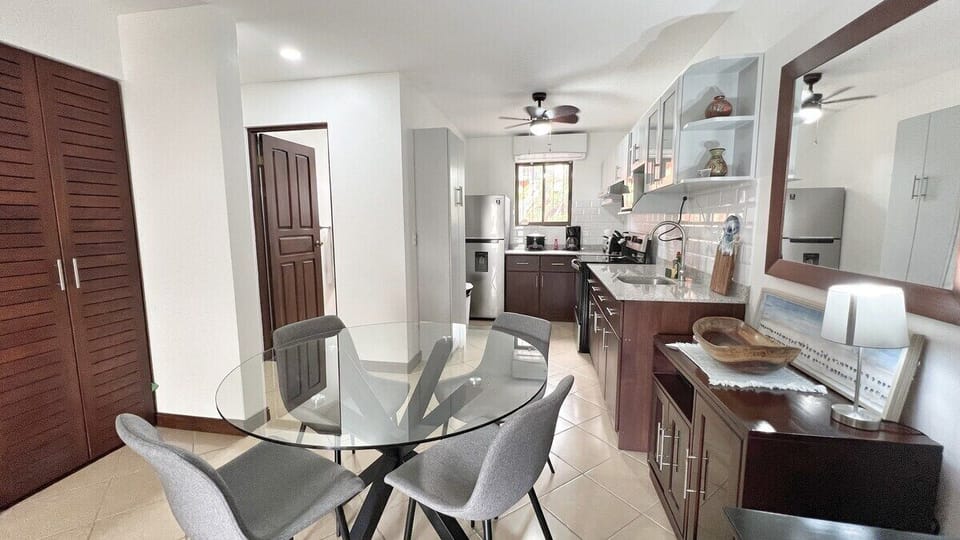 The condo has an open concept living space with the kitchen, dining and living room flowing out to the shaded patio.