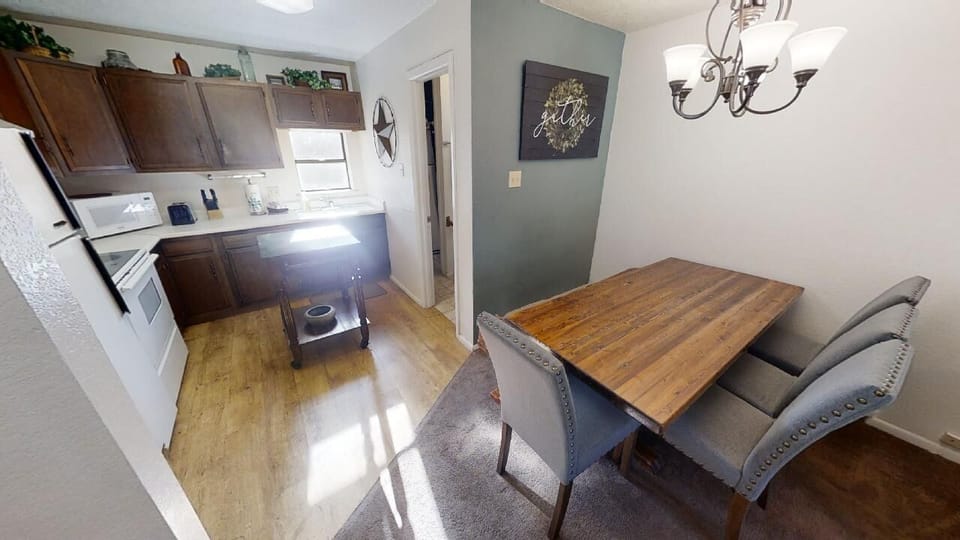Gather around your handsome wooden dining table for meals and conversation, while the well-equipped kitchen stands ready for all your cooking needs. Warm lighting and coastal-inspired decor create an inviting atmosphere for quality time together.