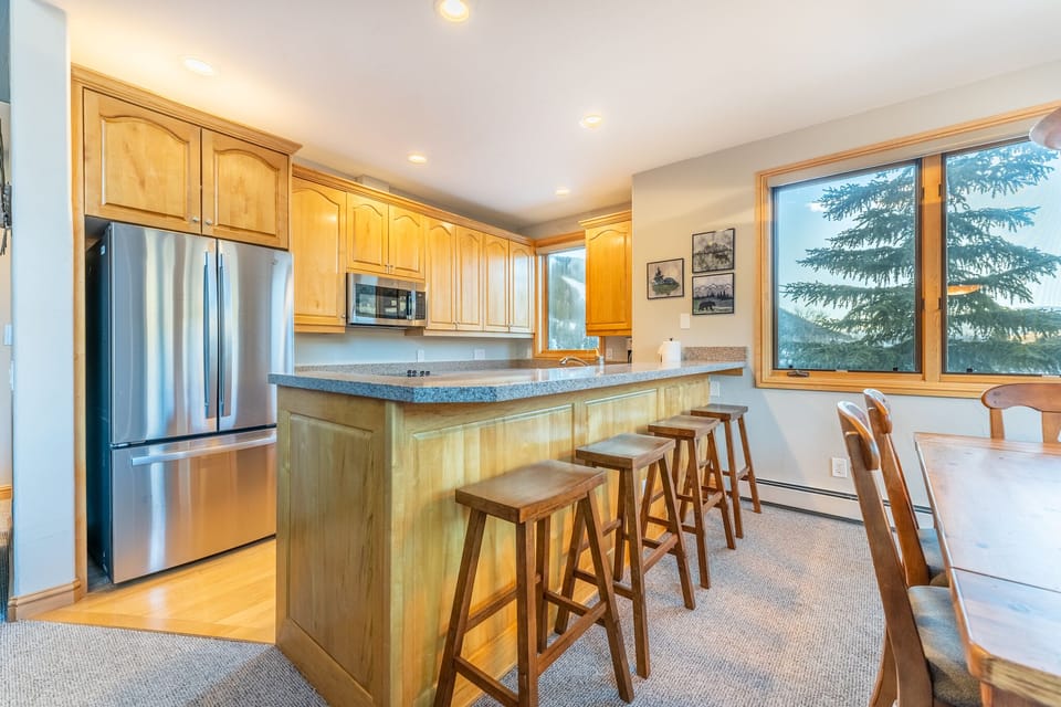 Your fully equipped kitchen features warm wood cabinets, granite counters, and a breakfast bar where you can enjoy morning coffee while gazing at the forest views.