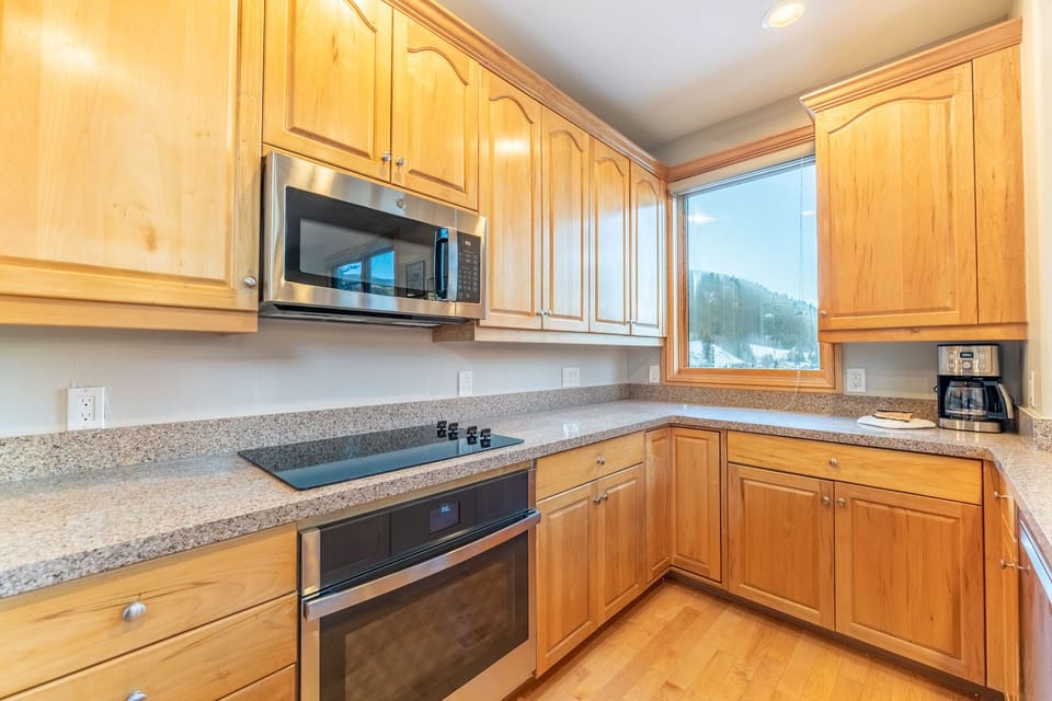 Cook your favorite meals in this fully equipped kitchen while enjoying stunning mountain views through the large window.
