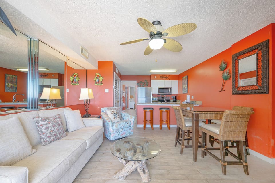 This vibrant living area features a cozy sofa, a large TV, and a stunning beachfront view from the sliding glass doors