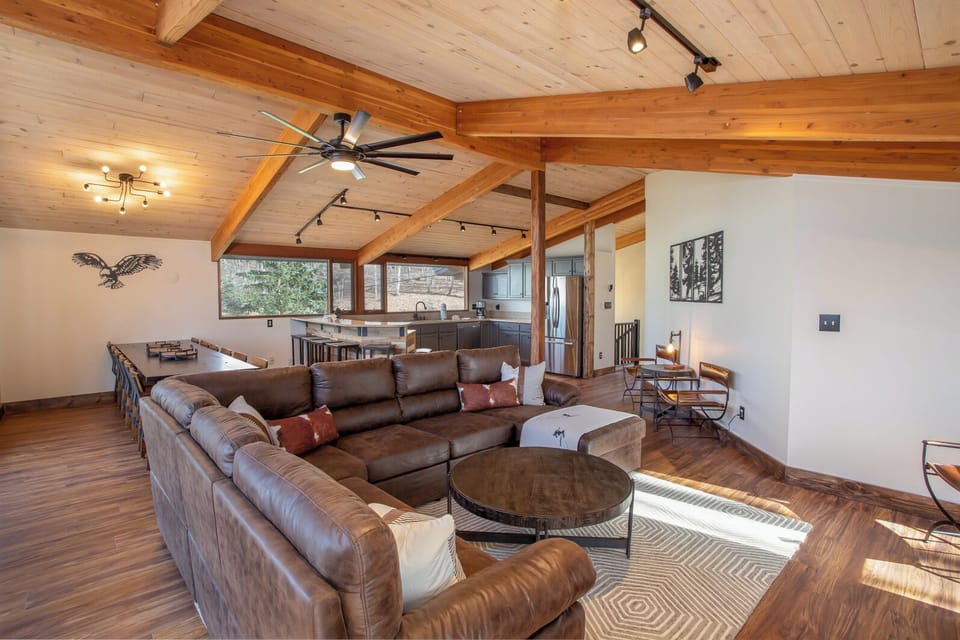 Open Kitchen, Dining, Living Room with Vaulted Ceilings, Exposed Beams, and Large Leather Sectional