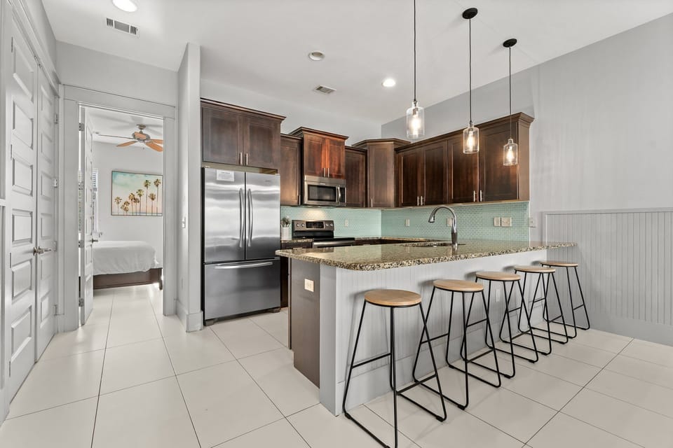 Kitchen with five barstools, entrance to downstairs king bedroom on the left