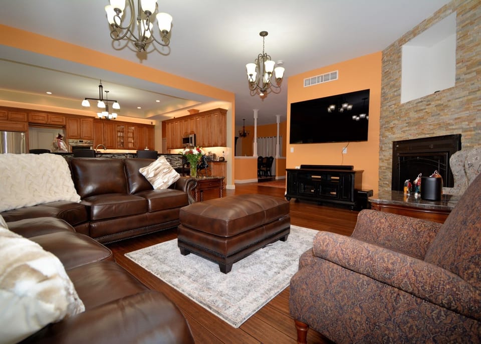 Living room with ample seating, 75 inch Smart TV, Sonos, and fireplace 