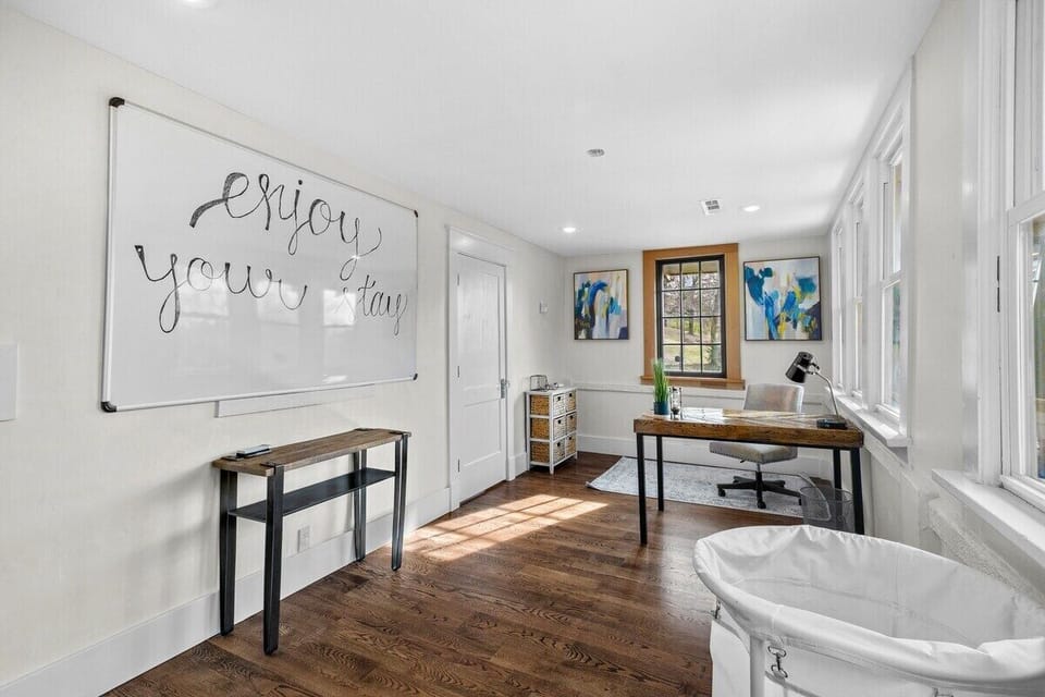 This room features a desk, swivel chair, large whiteboard, Samsung washer and dryer, laundry detergent, dryer sheets, rolling laundry bin and hooks to dry clothes.