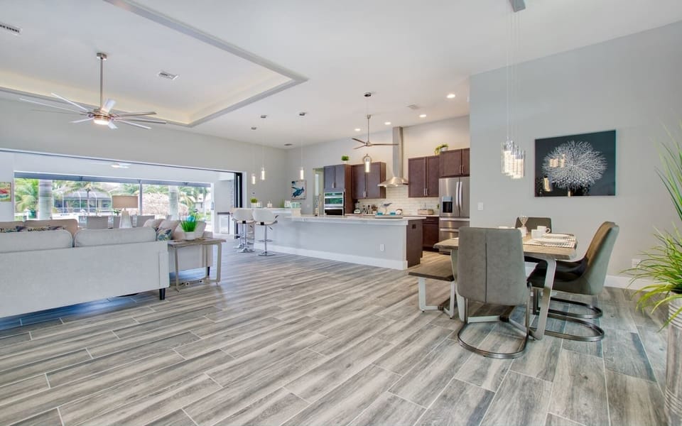 Open-plan kitchen and dining area with modern cabinetry, pendant lighting, and island seating