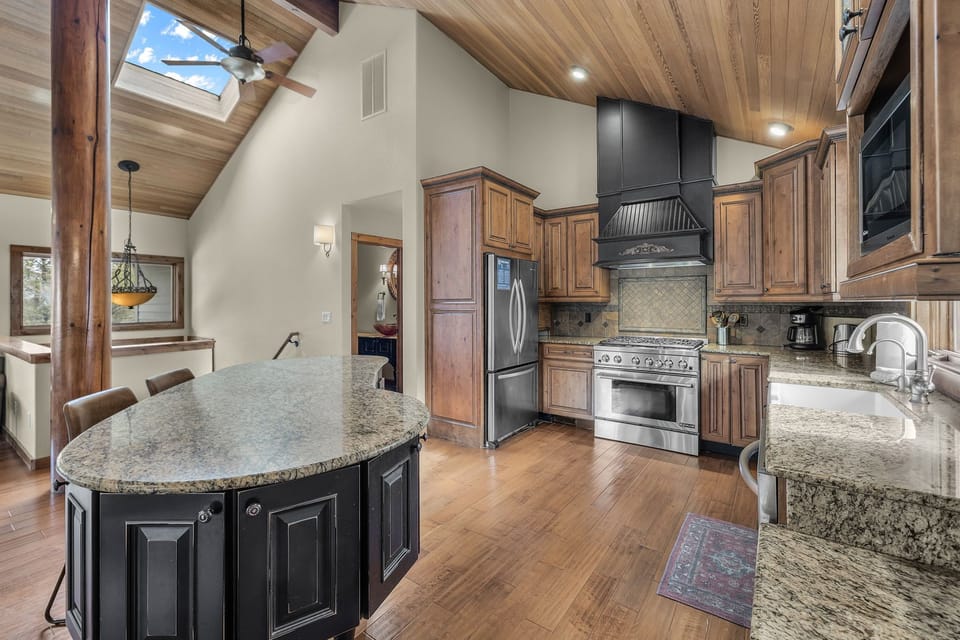 Gather around your gourmet kitchen island while natural light streams through skylights, illuminating rich wood beams and granite countertops perfect for memorable meals.