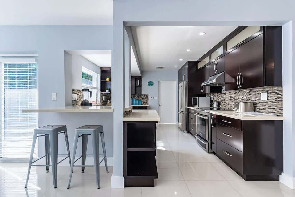 "Whip up meals in this sleek, modern kitchen with stainless steel appliances, breakfast bar, and natural light—perfect for family stays, remote work, or long-term vacation rentals!"