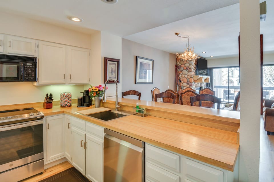 Stylish kitchen with stainless steel appliances flows into dining & living rooms