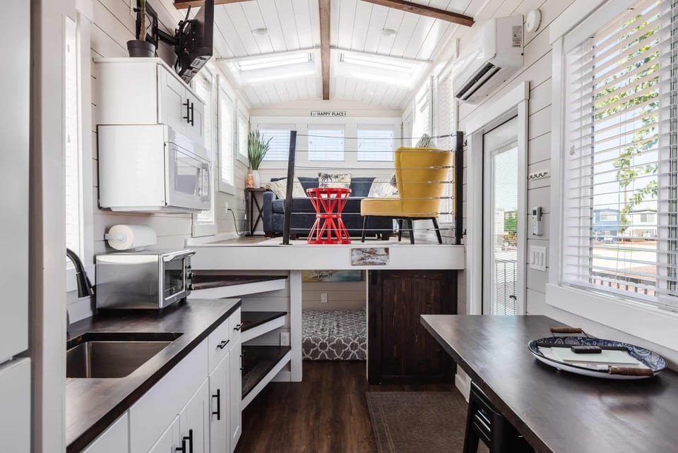 Welcoming living space with sectional seating, bright windows, and skylights overhead. Clean design and natural light make this living room feel open, comfortable, and relaxing.