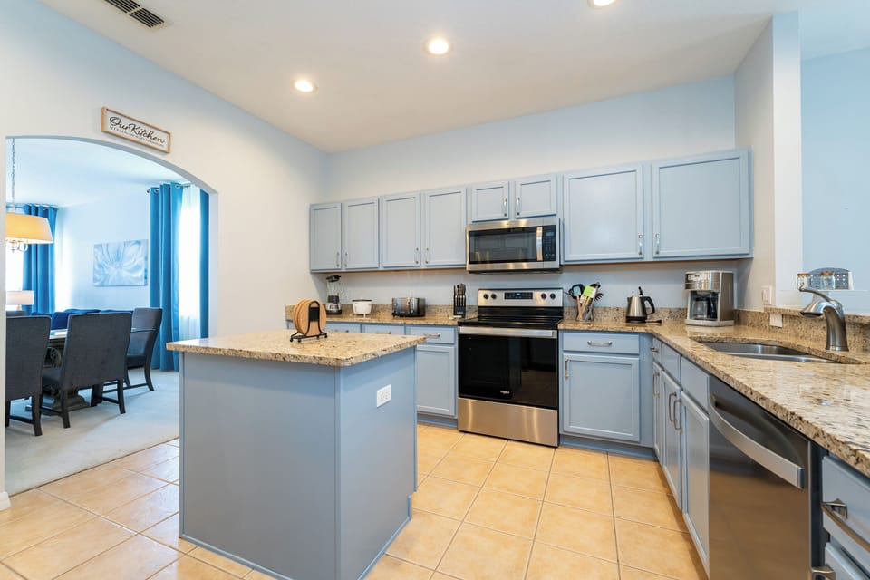 Open kitchen with granite countertops, center island, and stainless steel appliances.
