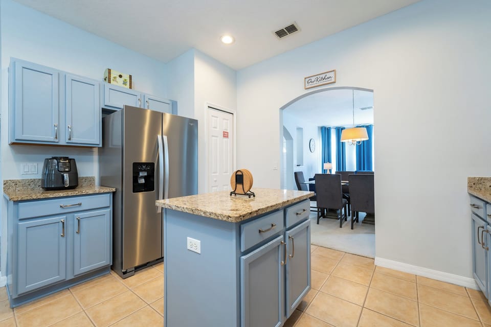 Kitchen island with granite countertops and stainless steel refrigerator.