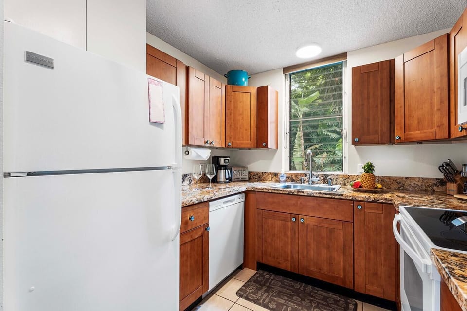 A cozy kitchen with warm wood cabinetry, granite countertops, and essential appliances.
