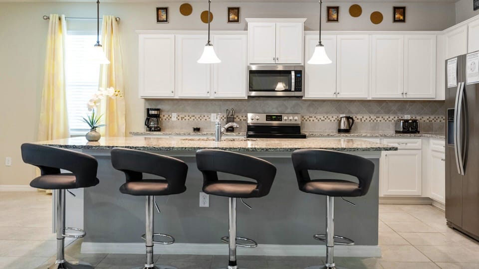 Modern kitchen with sleek granite counters, bar seating, and stainless appliances!