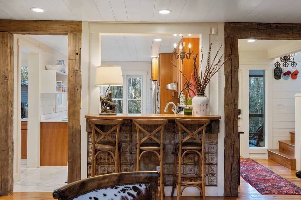 Rustic kitchen bar with wooden stools and decorative accents overlooking the cozy living space.
