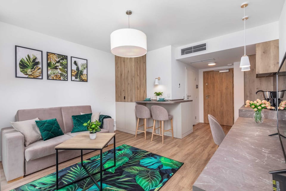 An open-plan living and dining area with a comfortable sofa, bright decor, and stylish wooden elements.

