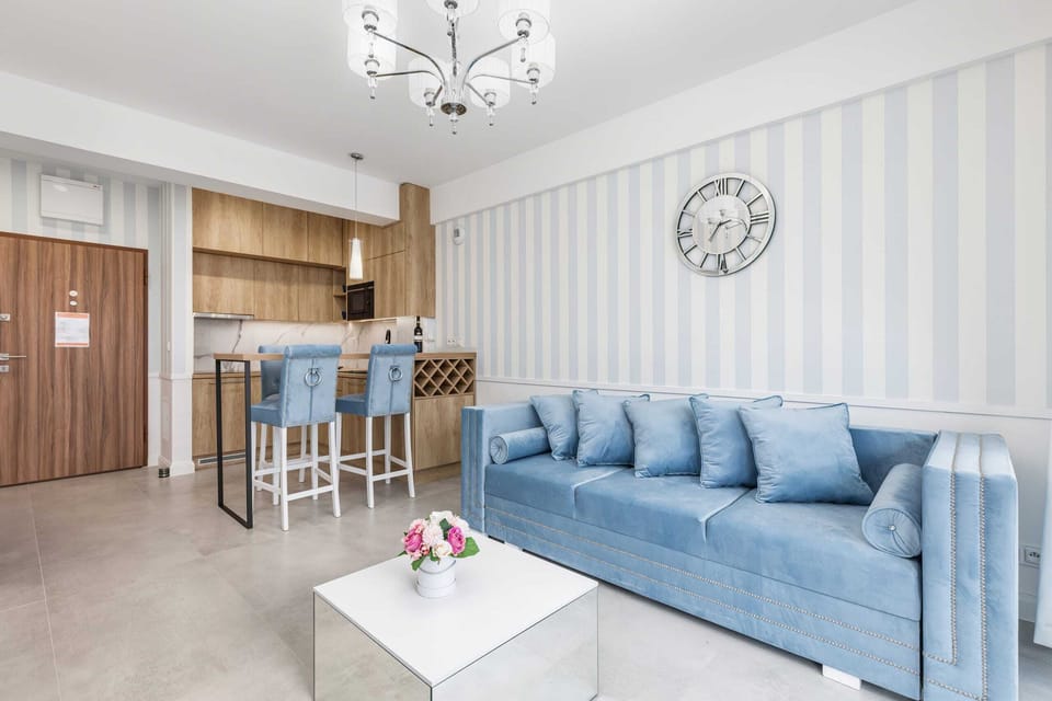 A bright living room featuring a light blue sofa, a white coffee table, and a large window allowing natural light to fill the space.