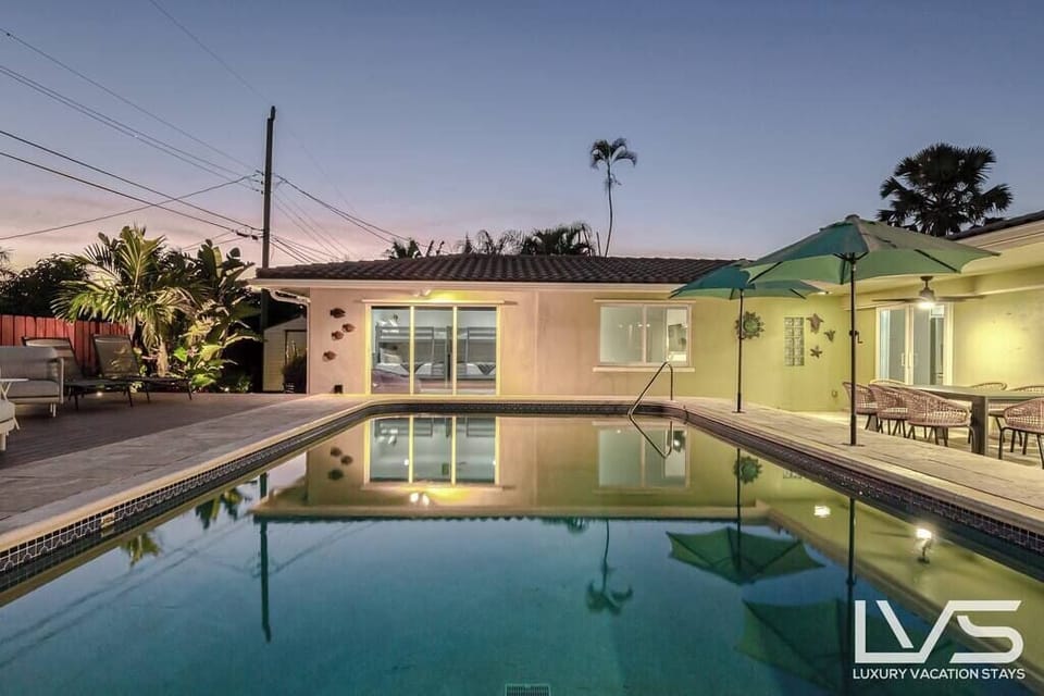 Tropical Fenced in Private Backyard with Heated Pool, uplighting, outdoor dining table, lounge chairs and plenty of seating/hammocks. 
