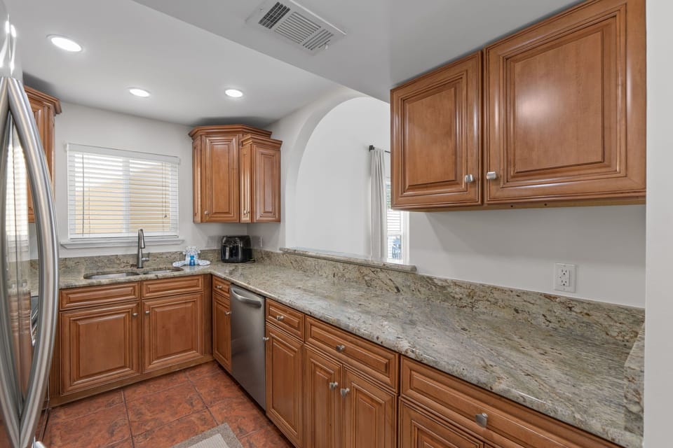 Step into your fully equipped kitchen with granite countertops, warm wood cabinets, and modern appliances ready for memorable meals.