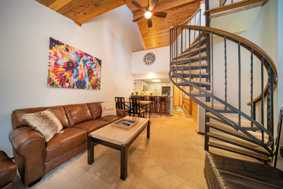 Relax in your cozy living area with plush leather seating and vibrant artwork before heading upstairs via the elegant spiral staircase.