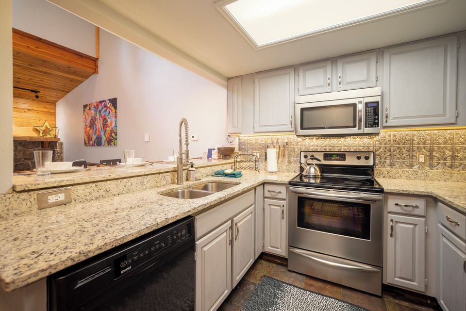 Your fully equipped kitchen features granite counters, stainless appliances, and charming tin ceiling tiles, perfect for preparing home-cooked meals.