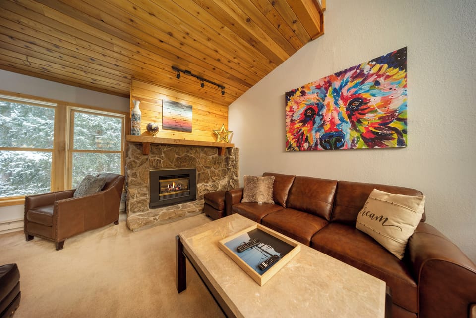 Cozy up by the stone fireplace in your stylish living room, where rich leather seating meets vibrant artwork.