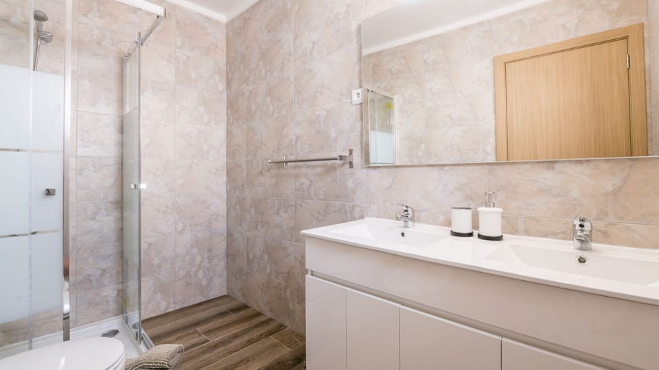 A modern bathroom with a spacious shower and sleek dual sinks, perfect for refreshing after a day of exploring.
#Bathroom #ModernDesign #LovelyStay
