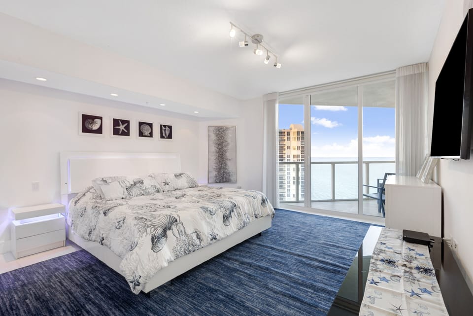 master bedroom with king bed, balcony, and attached bath