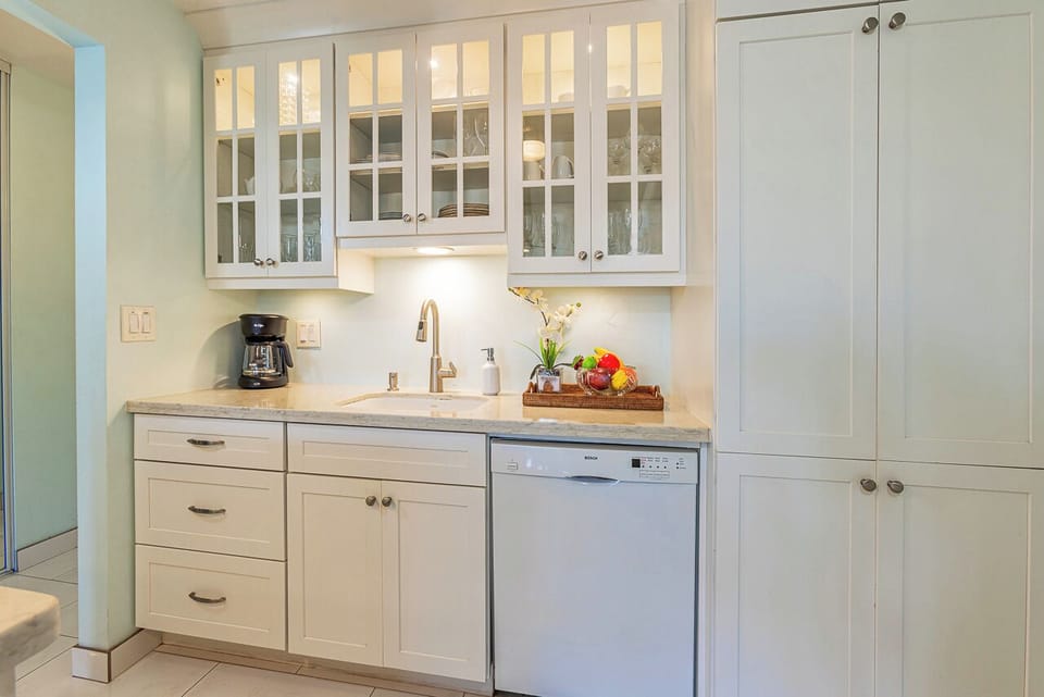 Your bright, modern kitchenette features pristine white cabinetry, marble countertops, and everything you need to feel at home—including a dishwasher for effortless cleanup.