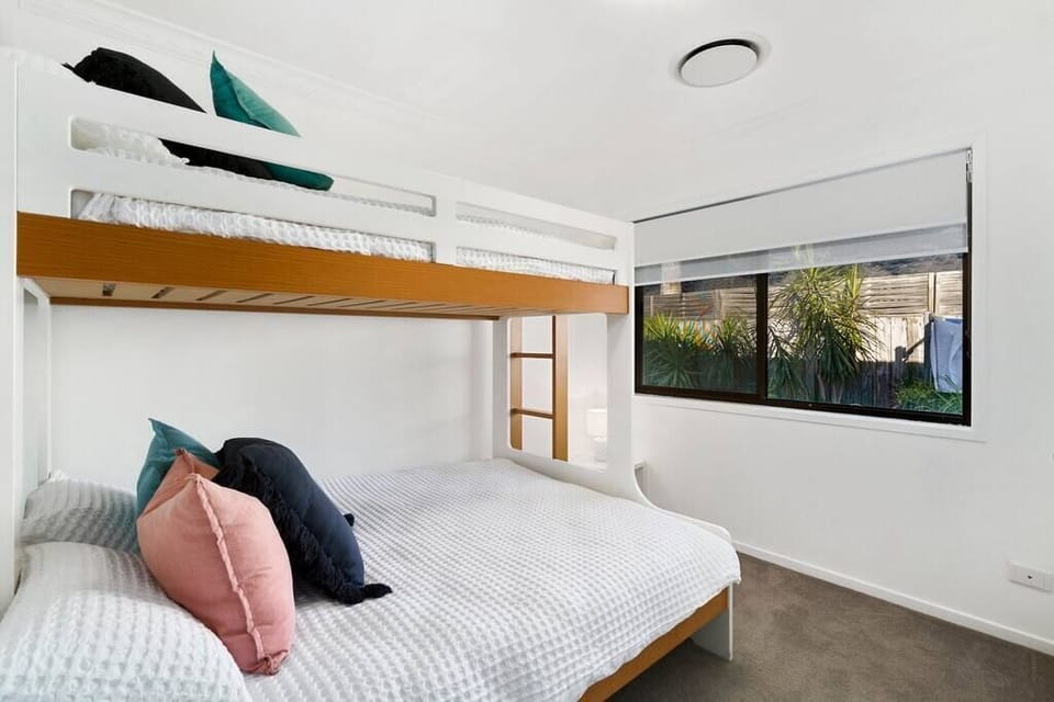 Bunk room with lower double, upper single, ceiling fan and wide window.