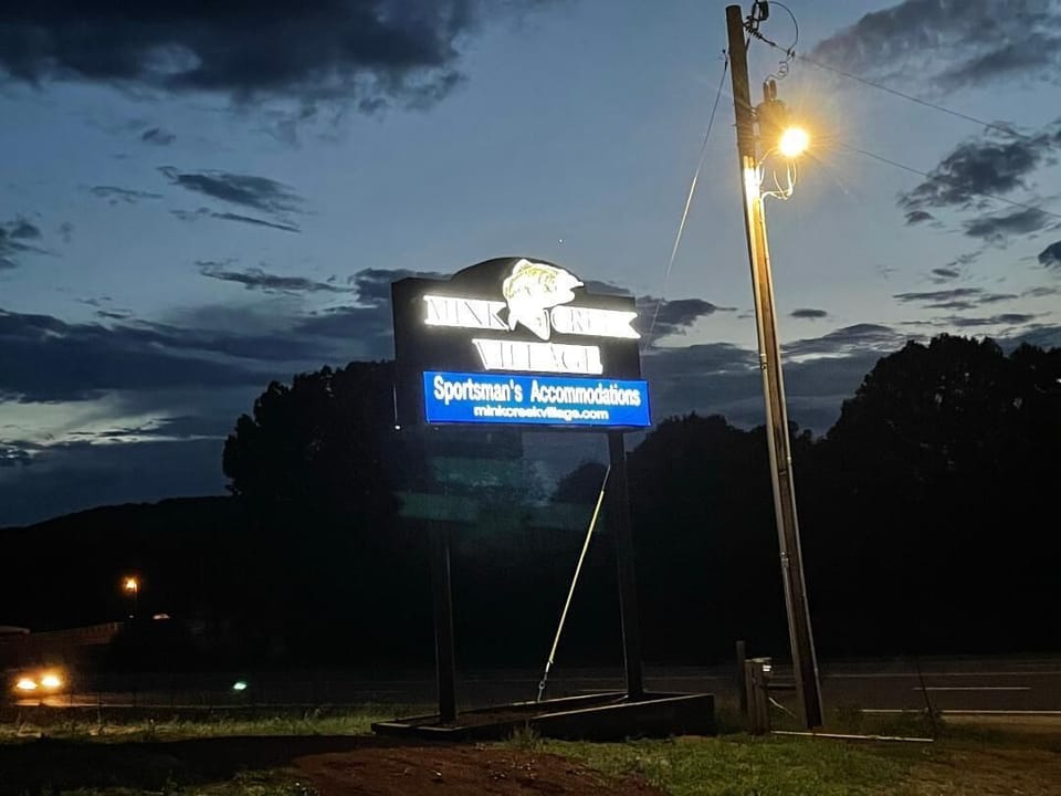 Mink Creek Village sign lights up at night.