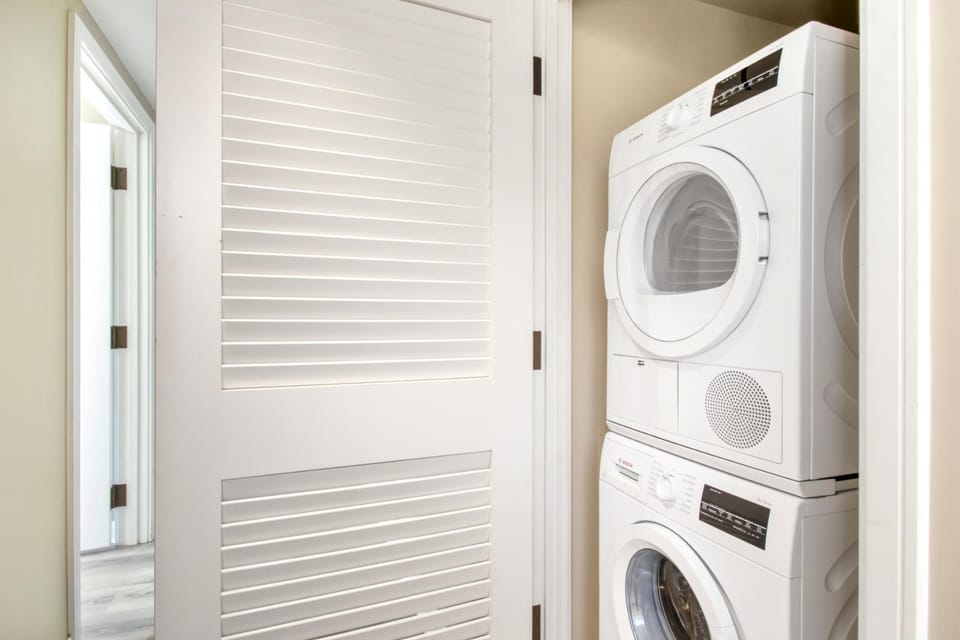 Compact laundry closet with stacked Bosch washer and dryer units.